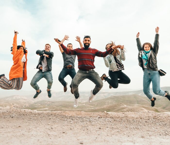 six group of people jumping on hill